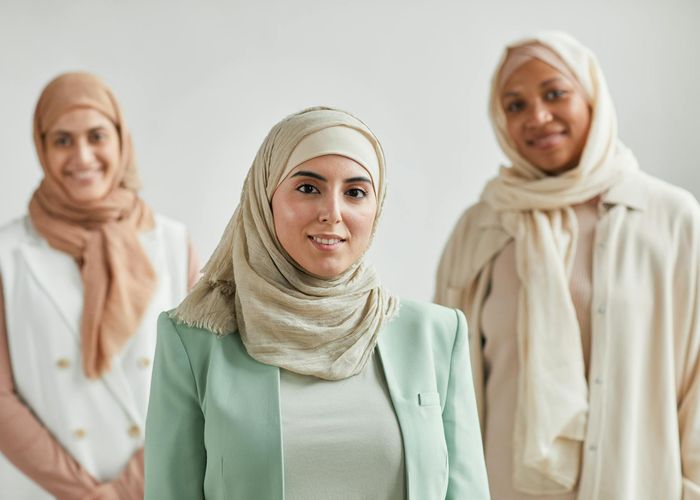 A group of diverse people smiling in a bright, modern yoga studio.