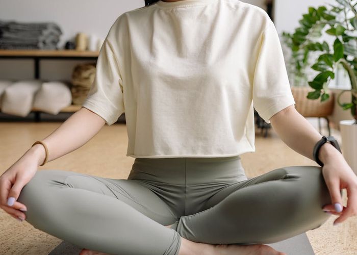 A person sitting in a meditative yoga pose with a calm and focused expression.