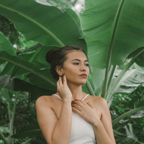 Woman in a calming yoga pose, surrounded by illustrative green leaves on a serene olive background.